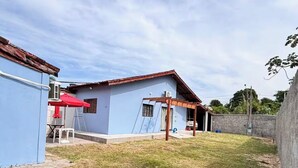 A residential property with a blue exterior, a wooden pergola, and a grassy yard. - Complete private house - Air conditioning. Wi-Fi - 3 bedrooms (Ilha Comprida)