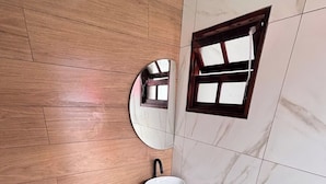 A bathroom with a wooden floor, a white sink, a mirror, and a window. - Complete private house - Air conditioning. Wi-Fi - 3 bedrooms (Ilha Comprida)