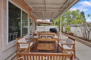 Une terrasse extérieure avec des meubles en bois, un espace abrité et une vue sur la verdure environnante.