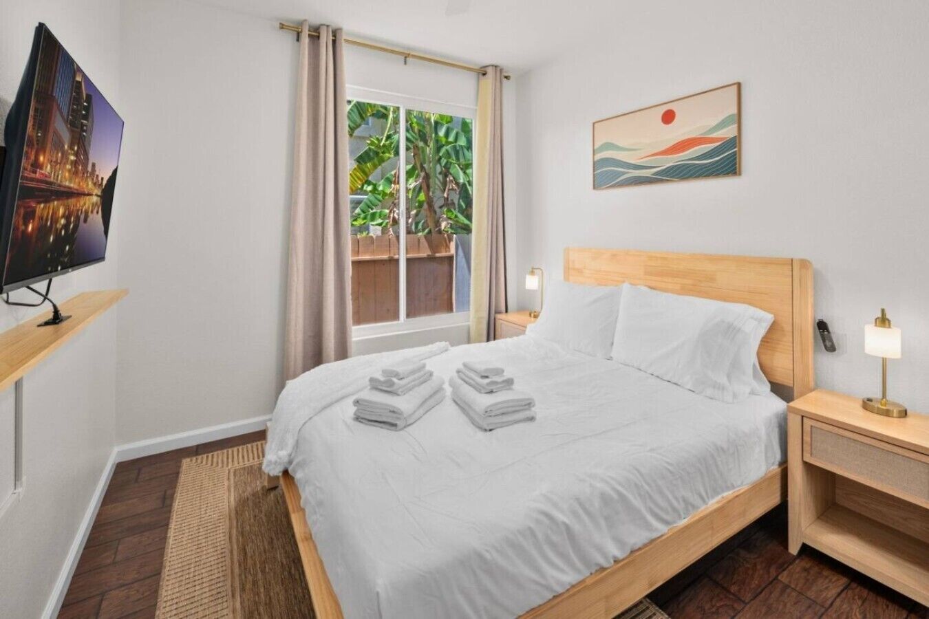 A hotel room with a bed, a TV, a nightstand, a lamp, and a painting.