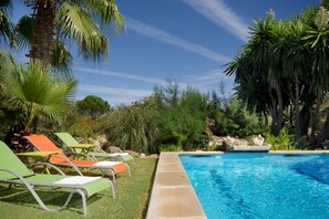A swimming pool with lounge chairs and tropical vegetation. - Traditional Villa With Pool in Pollensa (Pollença)