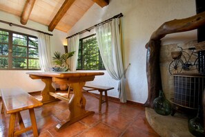 A rustic dining area with a wooden table and benches, large windows with curtains, and a bicycle on a stone ledge. - Traditional Villa With Pool in Pollensa (Pollença)