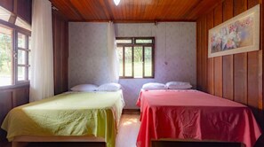 A room with two beds, a window, and a painting on the wall.
