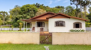 Une maison de plain-pied avec un porche, deux fenêtres et un portail en bois.