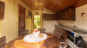 Un coin repas avec une table en bois, des chaises et un saladier rempli de fruits.