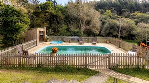 A backyard with a swimming pool, a wooden deck, and a fenced area. - Ranch with Pool, Lake and Trail | Jardim da Colina (Campina Grande do Sul)
