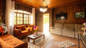 A cozy living room with a sofa, a coffee table, and a television mounted on the wall.