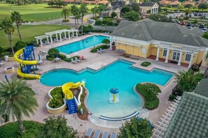 A large swimming pool with a water slide and a fountain, surrounded by lounge chairs and palm trees. - Rosemont Retreat-5BR Private Pool Home Near Disney with Golf Resort Amenities (Davenport)
