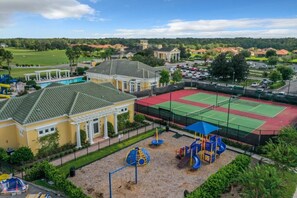 A playground with a tennis court, a pool, and a building with a green roof. - Rosemont Retreat-5BR Private Pool Home Near Disney with Golf Resort Amenities (Davenport)