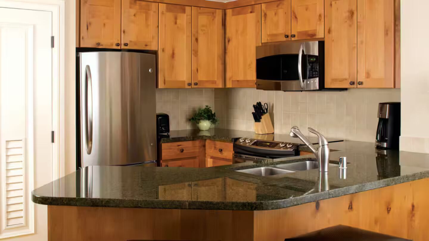 A kitchen with wooden cabinets, stainless steel appliances, a granite countertop, and a built-in microwave.