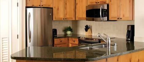 A kitchen with wooden cabinets, stainless steel appliances, a granite countertop, and a built-in microwave.