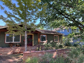 A house with a stone front, a red door, and a porch with a chair. - artist's home (Boulder)