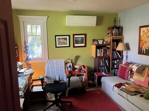Een kamer met een bureau, stoel, boekenkast en een bank.