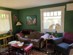 A living room with a sofa, a table with papers, a lamp, and a painting on the wall. - artist's home (Boulder)