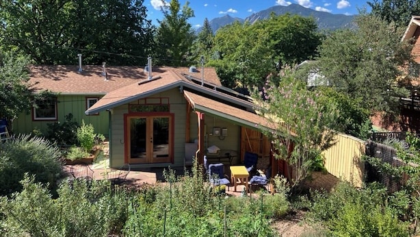 Et hus med en patio, et overdækket område og udsigt til et bjerg.