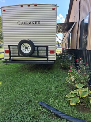 Un remolque con la leyenda 'CHEROKEE' en la parte trasera, estacionado sobre césped con un edificio al fondo.