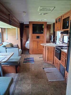 A compact RV interior with a kitchenette, a dining area, and a sleeping space. - Marvelous 2-bedroom recreational with AC in Thornville (Thornville)