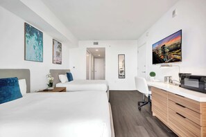 A hotel room with two beds, a desk with a computer, a TV, and artwork on the walls. - Lovely Modern Studio - Canal View & Beach Access (Hallandale Beach)