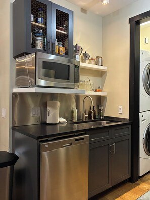 A compact kitchen with a built-in dishwasher, a microwave, and a washing machine.