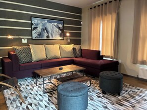 A modern living room with a sofa, ottoman, coffee table, and patterned floor.