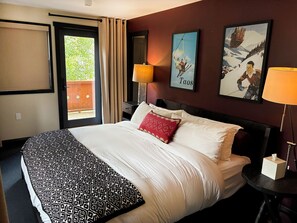 A hotel room with a bed, a nightstand, a lamp, and a window with curtains.