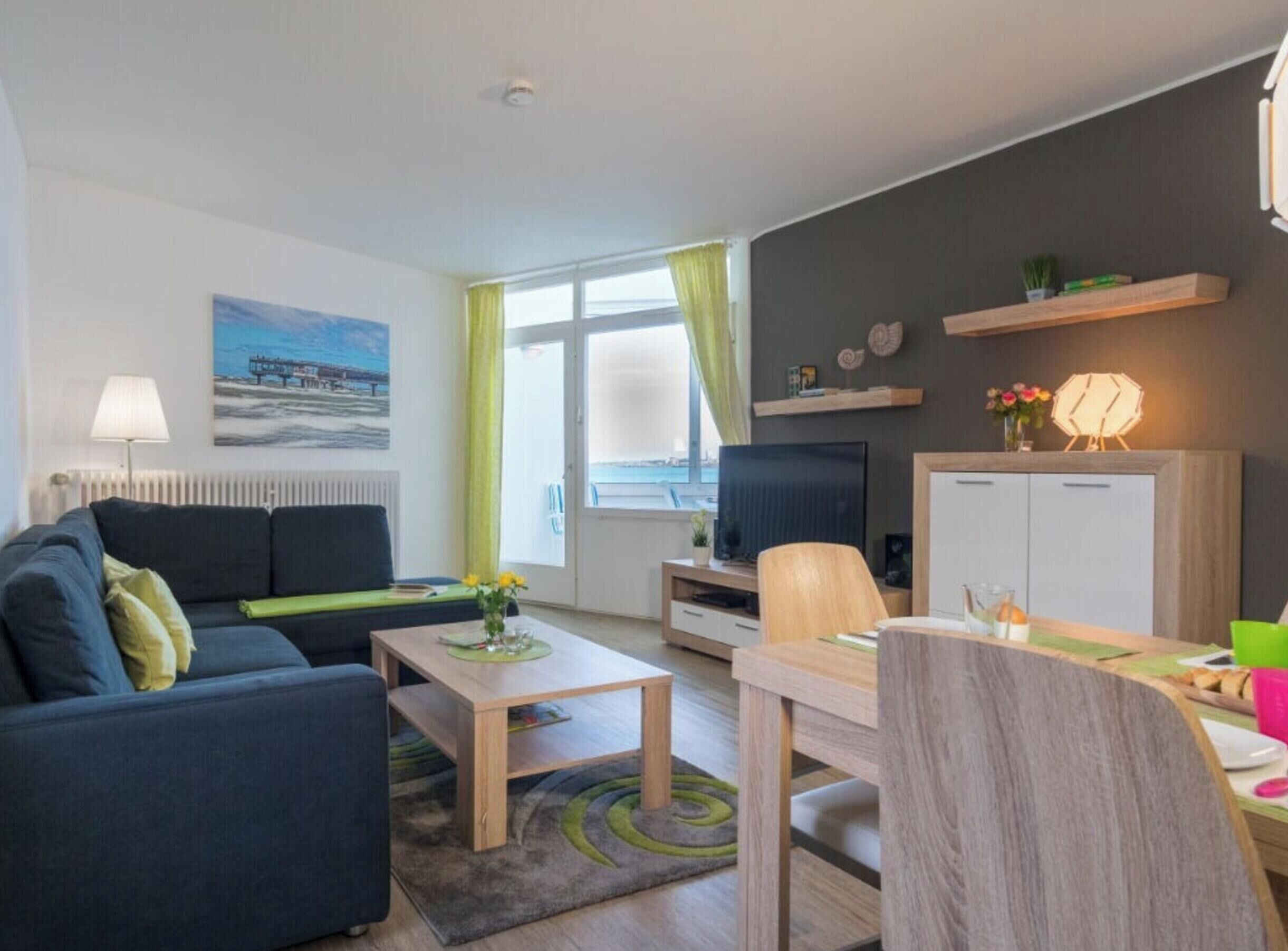 Una sala de estar moderna con un sofá, una mesa de centro, un televisor y un comedor con una silla y una mesa.