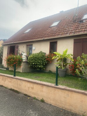 A house with a tiled roof, a fenced yard, and various plants. - Le Bonheur Vacation Rental (with free parking) (Sundhoffen)