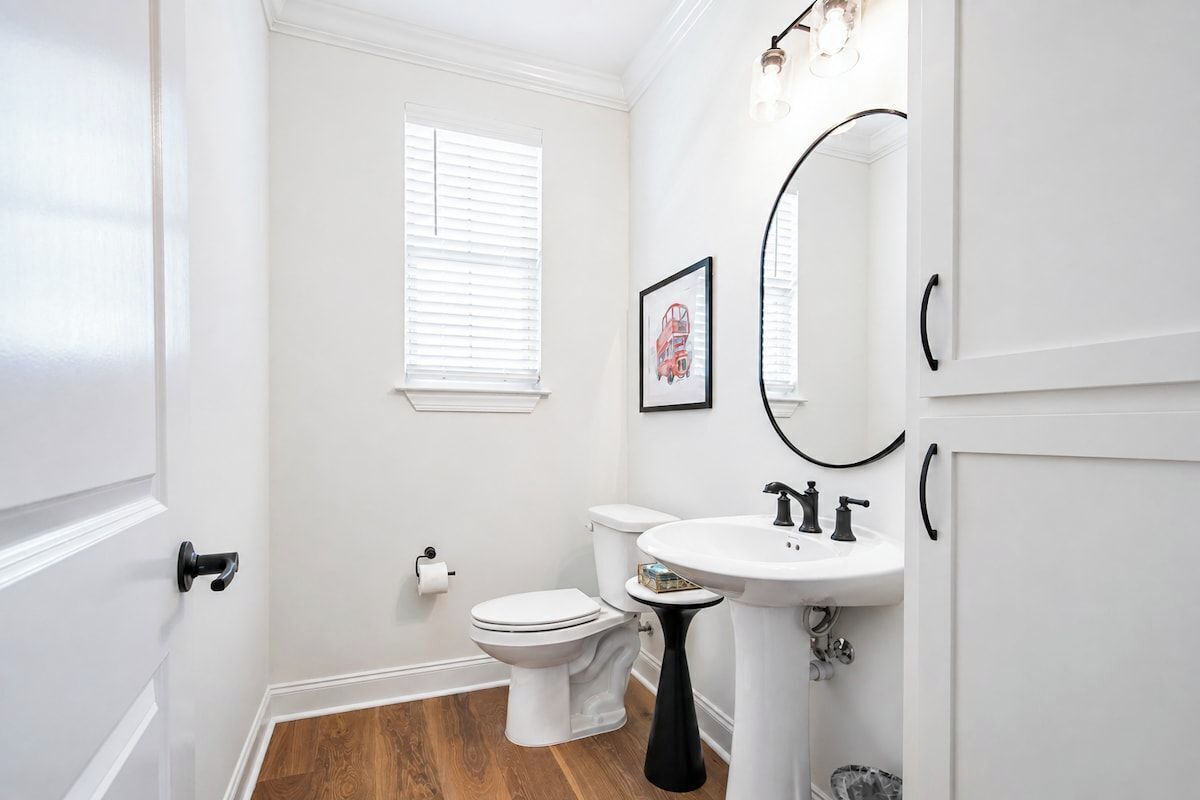 A bathroom with a toilet, sink, and a mirror.