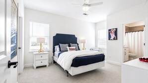 A bedroom with a bed, bedside tables, a ceiling fan, a window with blinds, and a bathroom visible through an open door. - The Summit House, 3BR by Velvet Ditch Villas (Oxford)