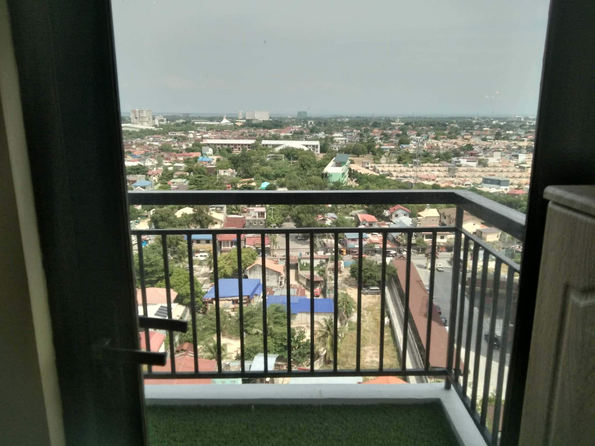 Un balcon donnant sur un quartier résidentiel, avec vue sur des maisons et des immeubles.
