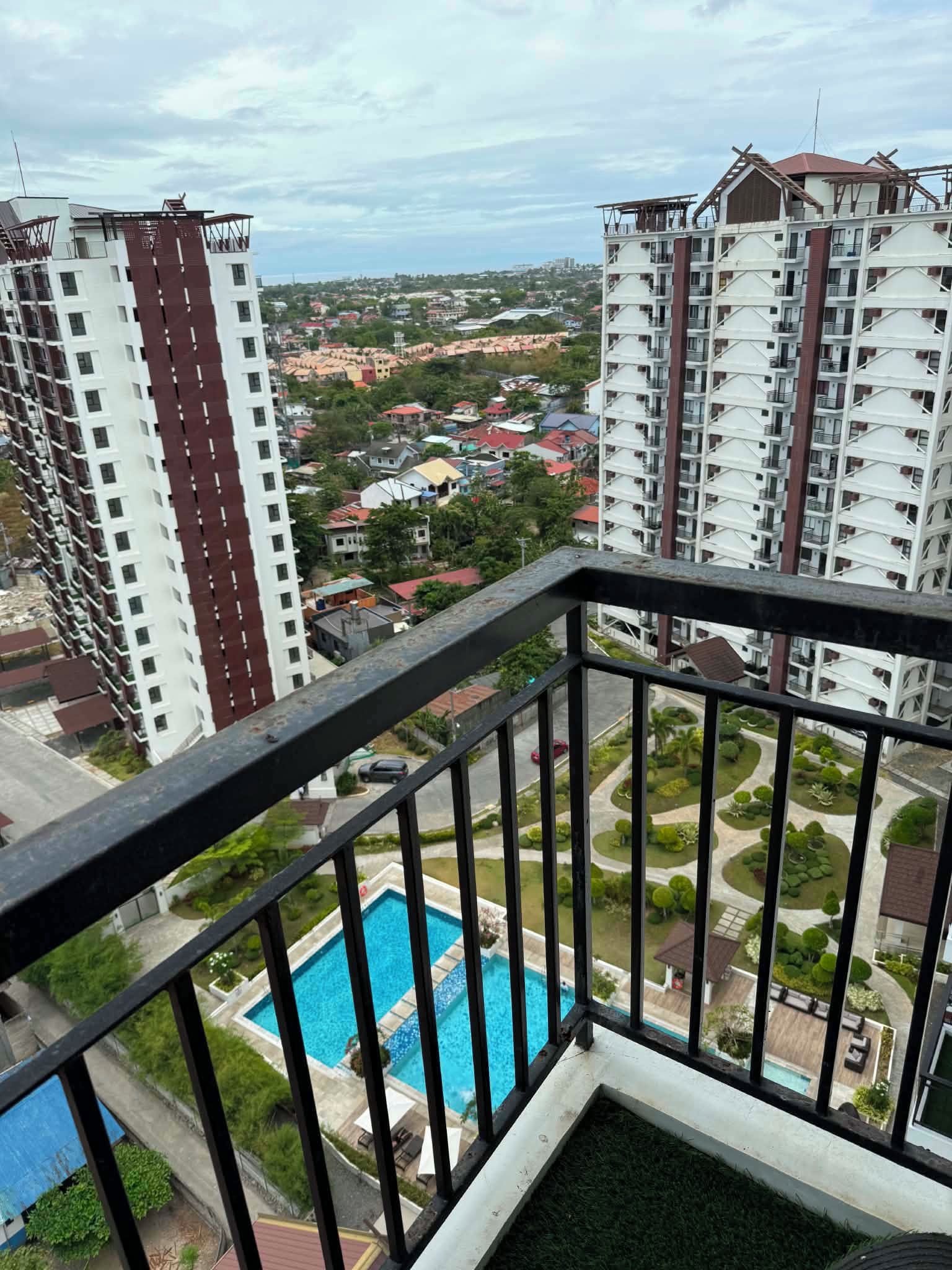 A residential building with a pool, surrounded by other high-rise buildings and a green landscape.