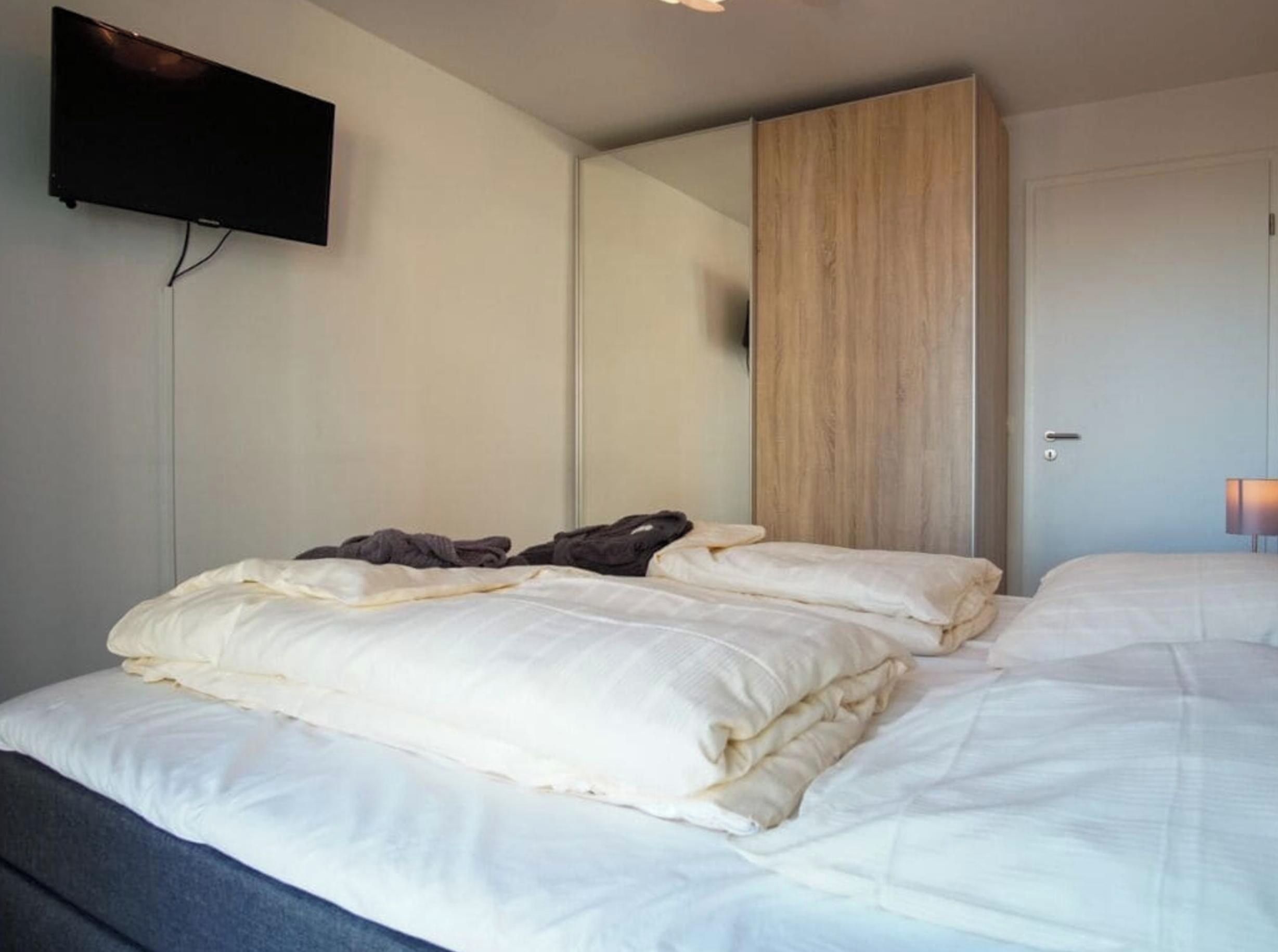 Een hotelkamer met een bed, een flatscreen televisie aan de muur en een houten paneel.