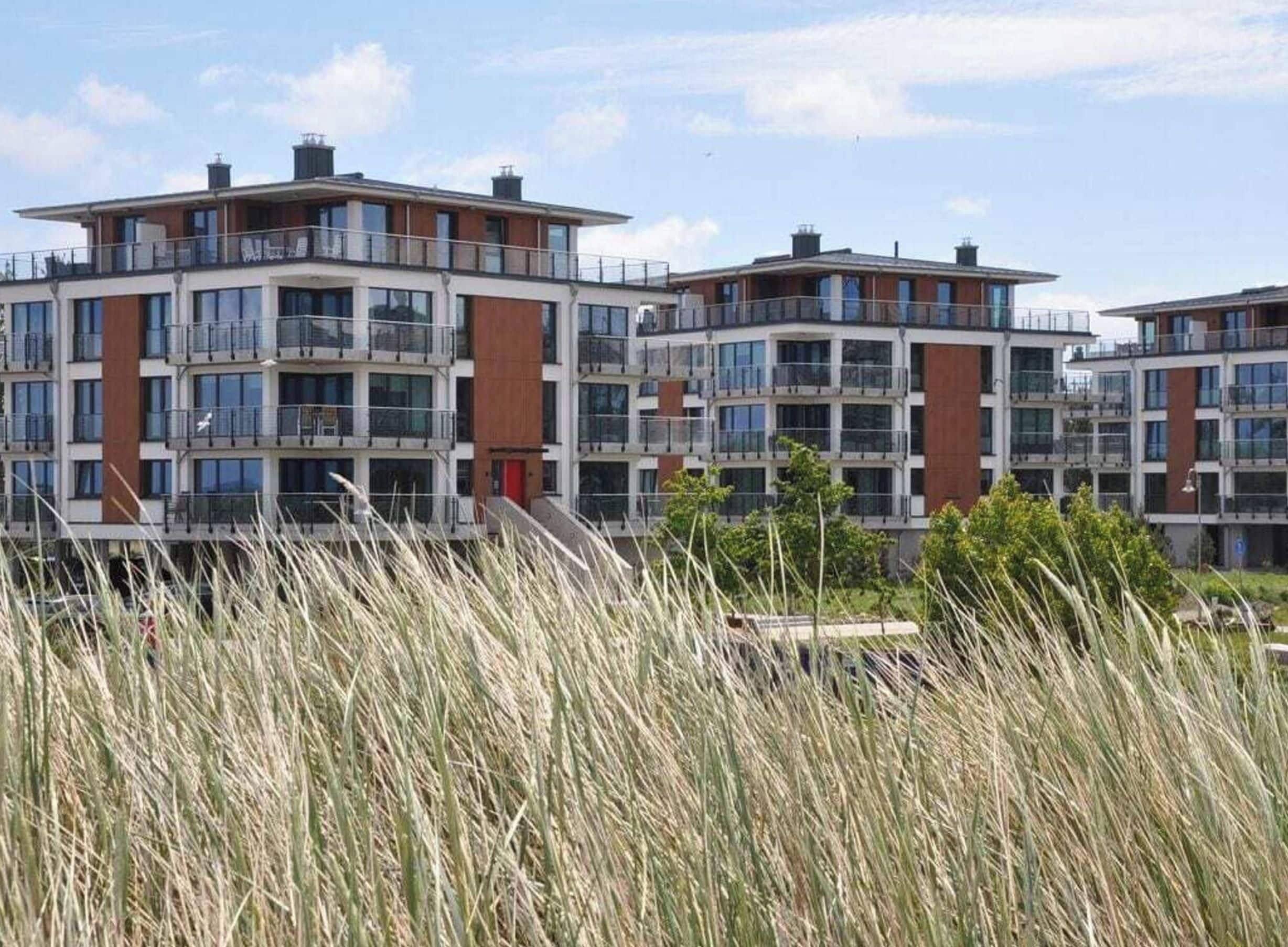 A multi-story residential building with balconies, large windows, and a flat roof.