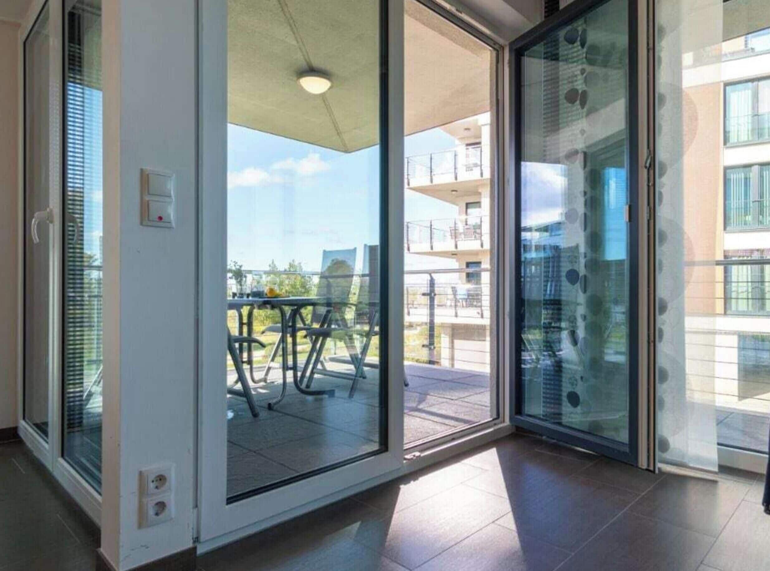 Et moderne interiør med en skydedør, der fører ud til en balkon med et bord og stole.