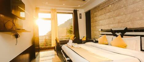 A hotel room with a bed, a ceiling fan, a window with curtains, and a view of the outdoors.