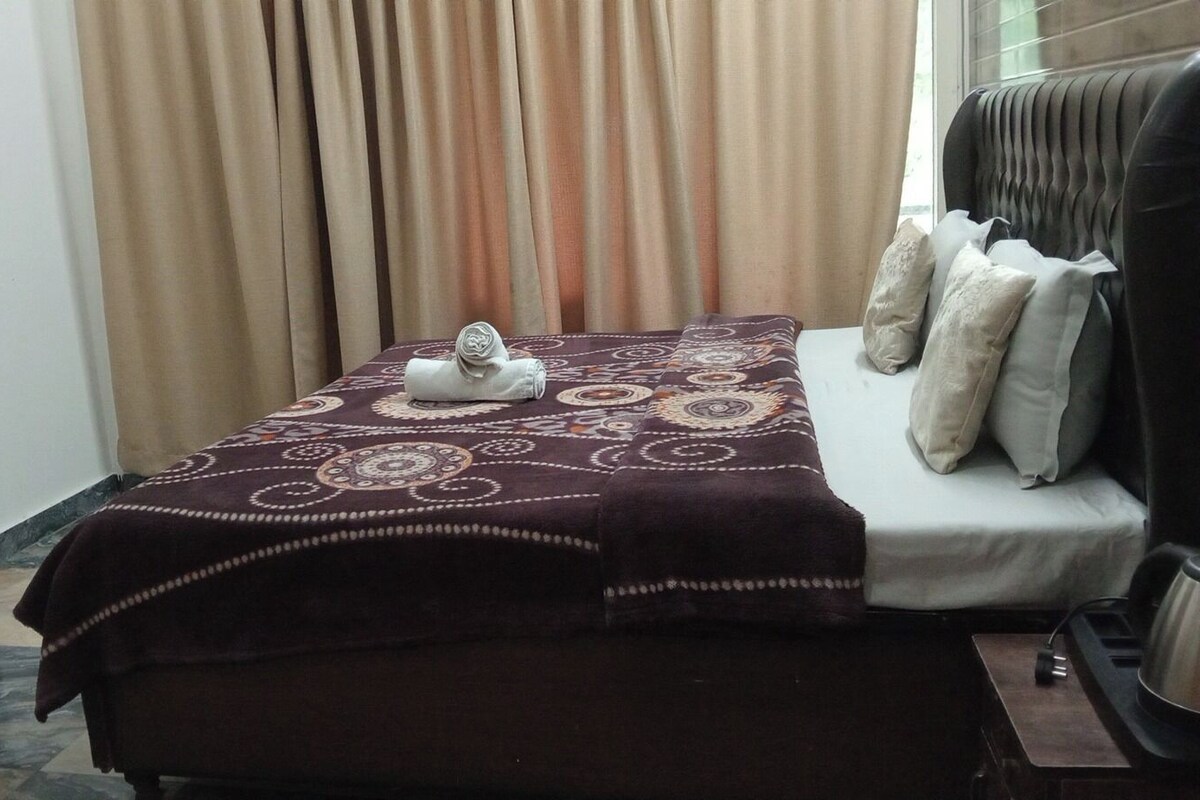 Ein Hotelzimmer mit Bett, Schreibtisch und einem Vorhangfenster.