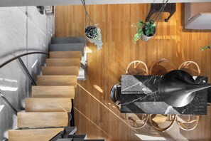 Ein modernes Interieur mit einer Holztreppe, hängenden Pflanzen und einem Marmortisch.