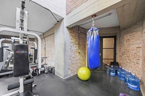 Ein Fitnessraum mit Trainingsgeräten, einem Boxsack und Wasserflaschen.