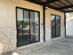 A building with stone and plaster exterior walls, large glass doors, and a covered patio area. - Peaceful 2-bedroom house with AC in charming Chelem,2 blocks away from the beach (Chelem)