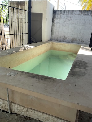 Une piscine extérieure rectangulaire, dotée d’un bord en béton et d’une clôture en métal.