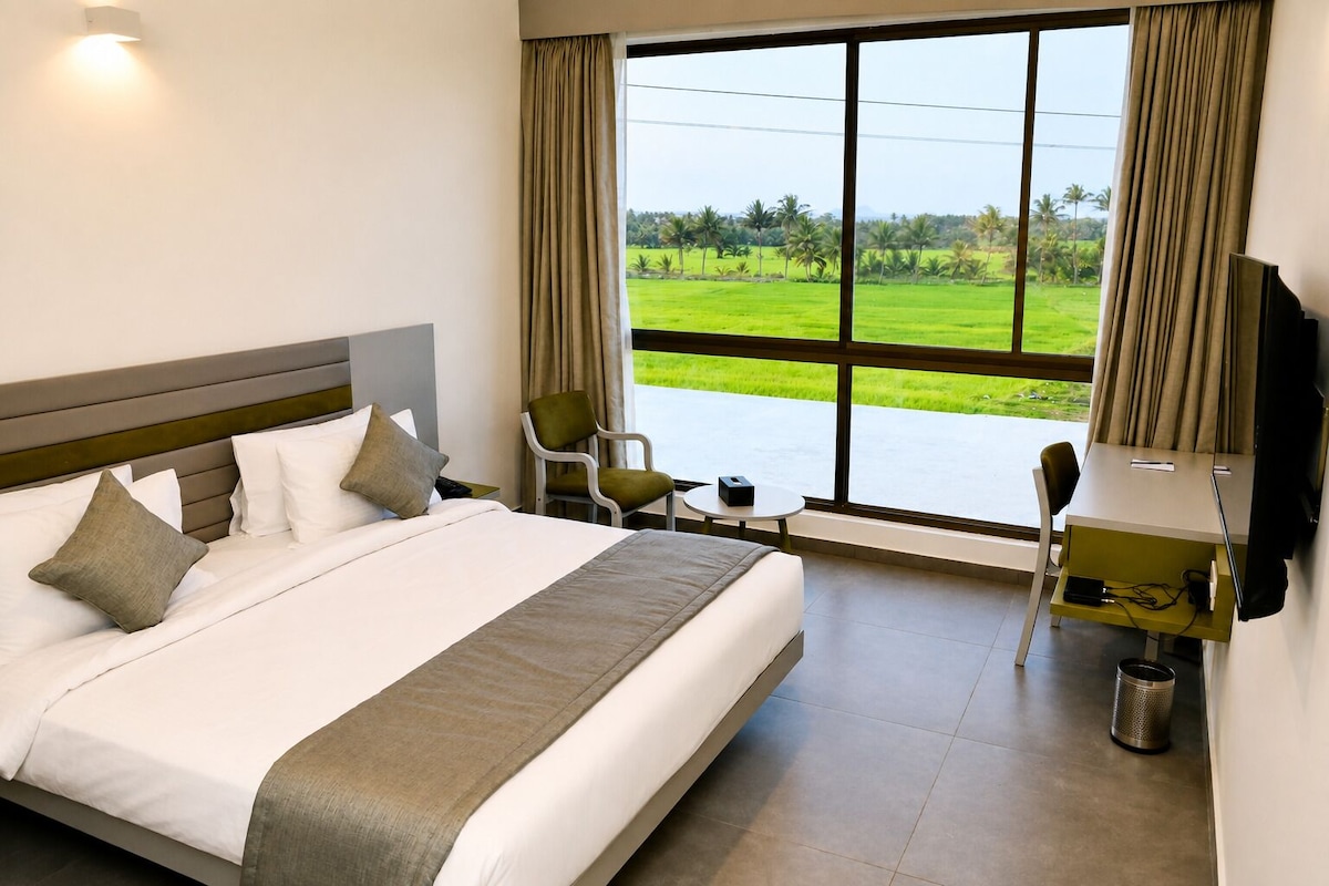 A hotel room with a large bed, a desk, a chair, and a TV.
