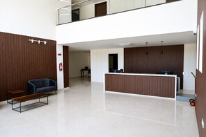 A modern reception area with a desk, seating, and a fire extinguisher. - Hotel Four Meadows (Mysuru)