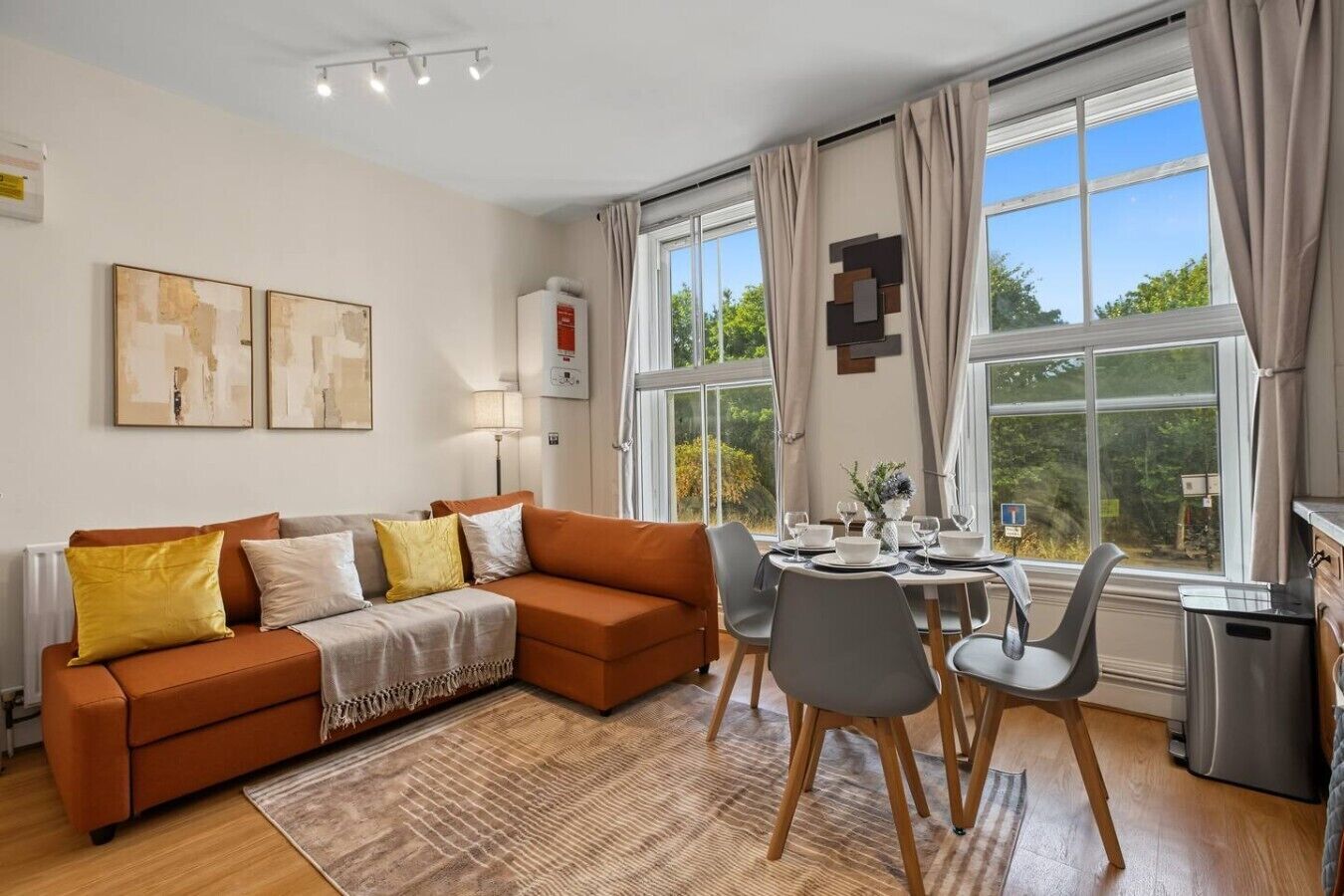 A modern living room with a sofa, dining table, chairs, and artwork on the wall.