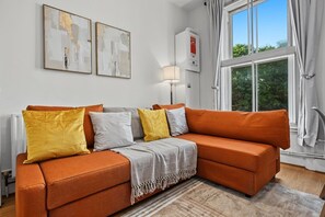 Ein modernes Wohnzimmer mit einer Eckcouch, einer Stehlampe und abstrakter Wandkunst.
