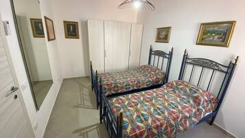 Une chambre avec deux lits, une armoire et une porte.