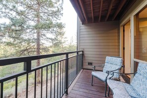 A wooden deck with a metal railing, two chairs with patterned cushions, and a view of trees. - Bend Adventure Starts Here - Near Mt Bachelor (Bend)
