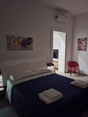 A bedroom with a bed, a chair, and artwork on the walls. - ALICJA HOUSE (Casoria)
