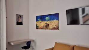 Ett modernt vardagsrum med en soffa, en tavla, en tv och ett skrivbord med en stol.