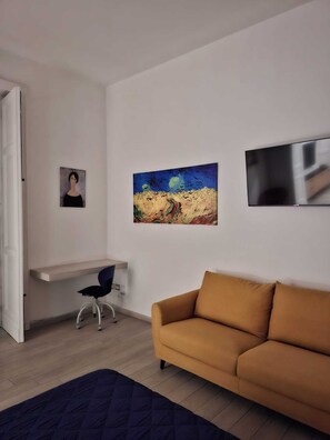 A modern living room with a sofa, a painting, a TV, and a desk with a chair. - ALICJA HOUSE (Casoria)