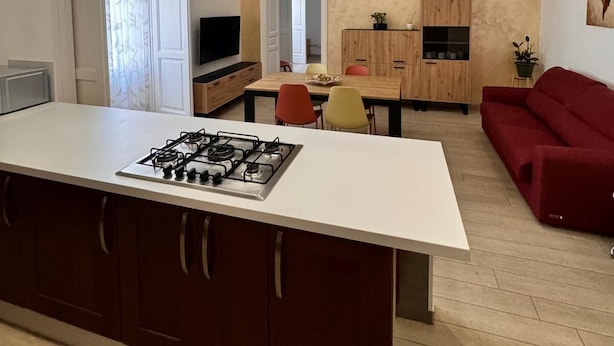Ett modernt kök med en central köksö, en inbyggd spis och en rostfri köksfläkt.